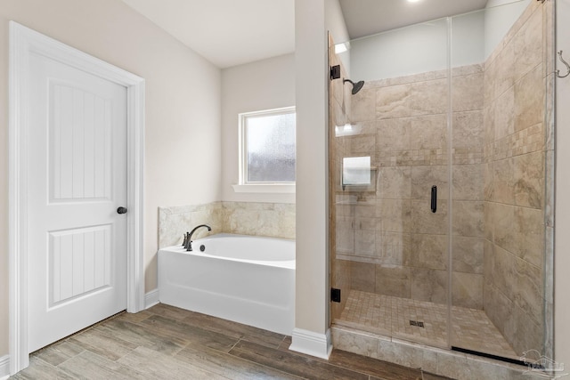 full bathroom featuring wood finished floors, a bath, and a shower stall