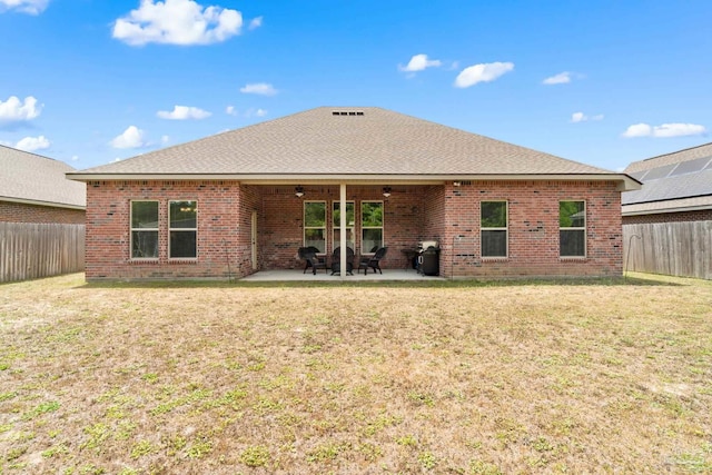 back of property featuring a lawn, a ceiling fan, a fenced backyard, and brick siding