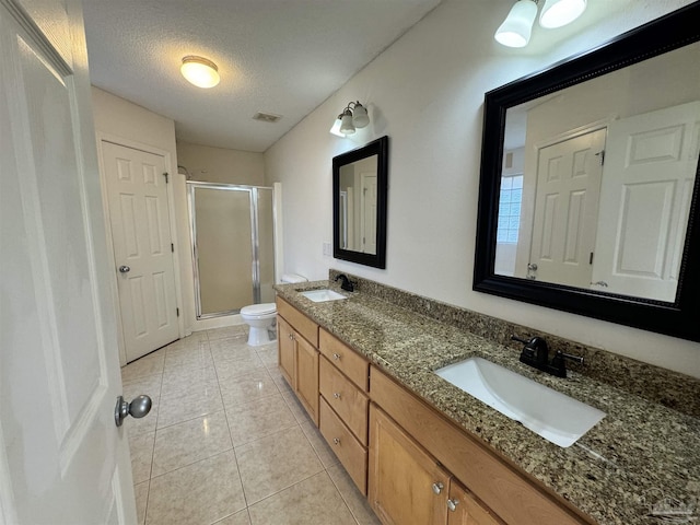 bathroom featuring a shower with shower door, tile patterned flooring, vanity, toilet, and a textured ceiling