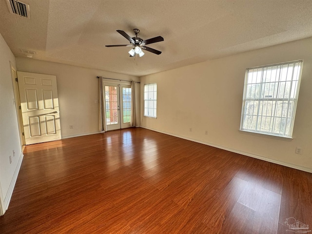 empty room with dark hardwood / wood-style flooring, ceiling fan, french doors, and a textured ceiling