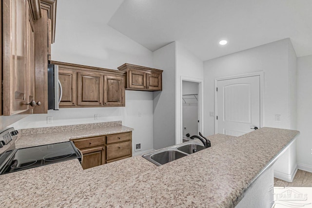 kitchen with appliances with stainless steel finishes, sink, lofted ceiling, and kitchen peninsula