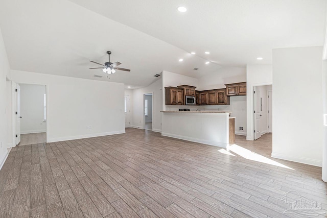 unfurnished living room with vaulted ceiling, light hardwood / wood-style floors, and ceiling fan