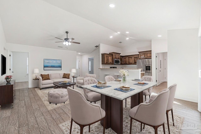 dining space with ceiling fan, lofted ceiling, and light hardwood / wood-style flooring