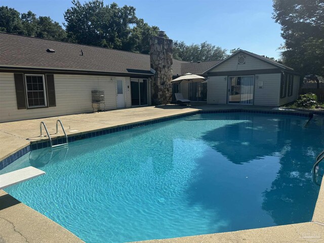 view of swimming pool with a diving board and a patio area