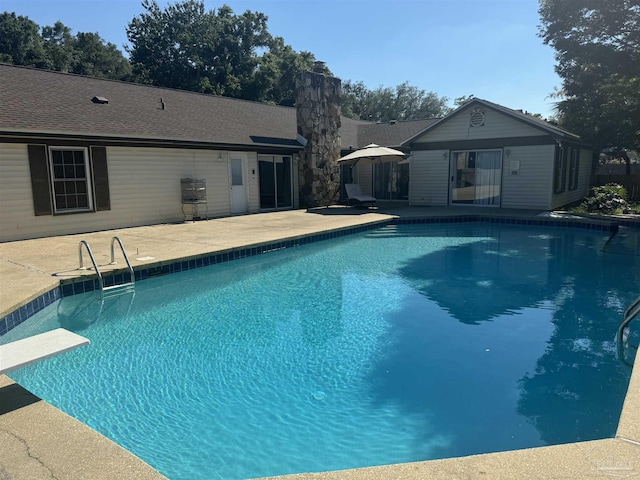 pool with a patio and a diving board