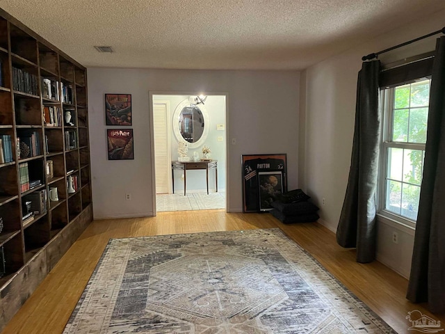 interior space featuring light wood-type flooring and a textured ceiling