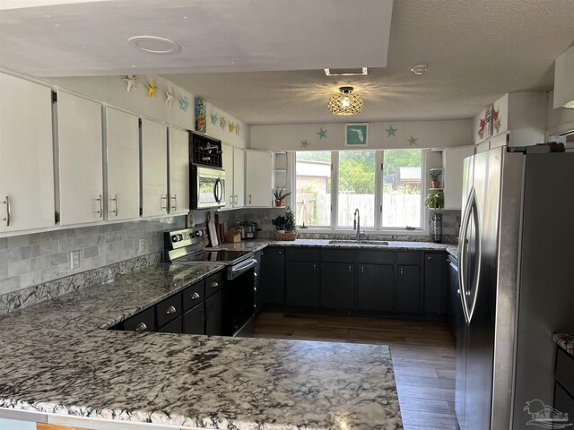 kitchen with white cabinets, light stone countertops, decorative backsplash, and appliances with stainless steel finishes