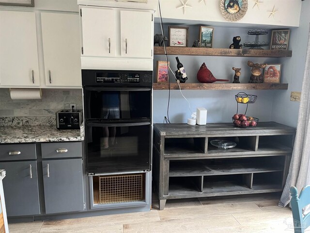 kitchen with white cabinetry, tasteful backsplash, light wood-type flooring, double oven, and gray cabinets