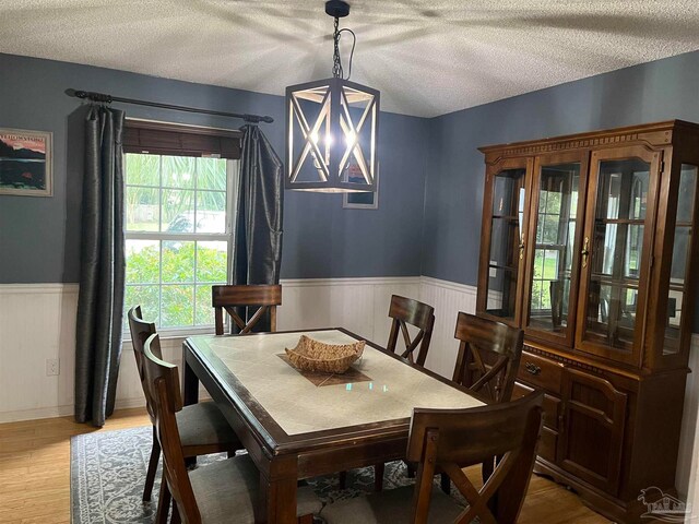 dining room with a textured ceiling, light hardwood / wood-style flooring, and a notable chandelier