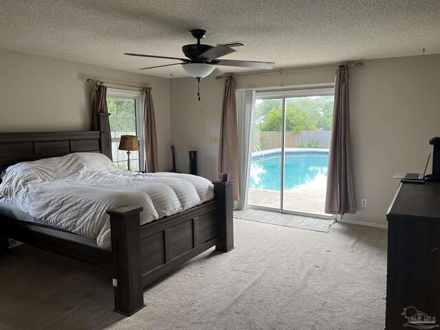 carpeted bedroom featuring a textured ceiling, multiple windows, access to outside, and ceiling fan