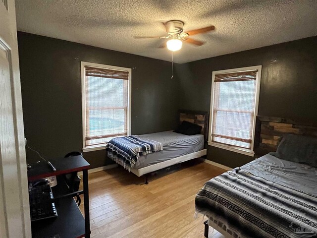 bedroom featuring a textured ceiling, light wood-type flooring, and ceiling fan