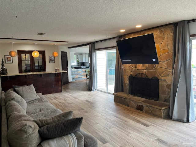 living room with a textured ceiling, a fireplace, and light wood-type flooring