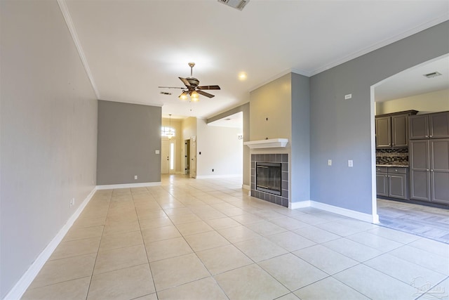 unfurnished living room featuring light tile patterned floors, crown molding, a fireplace, and ceiling fan