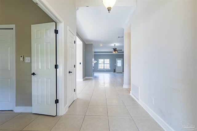 corridor featuring ornamental molding and light tile patterned floors