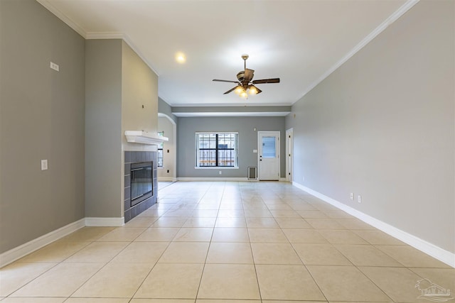 unfurnished living room featuring ceiling fan, ornamental molding, a fireplace, and light tile patterned floors