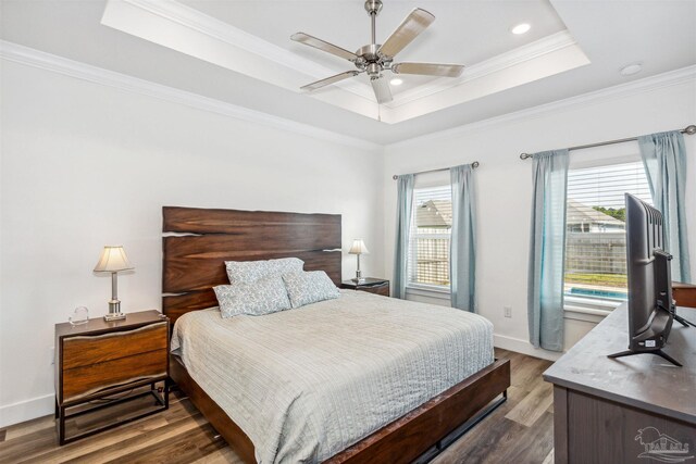 bedroom with wood-type flooring, a tray ceiling, crown molding, and ceiling fan