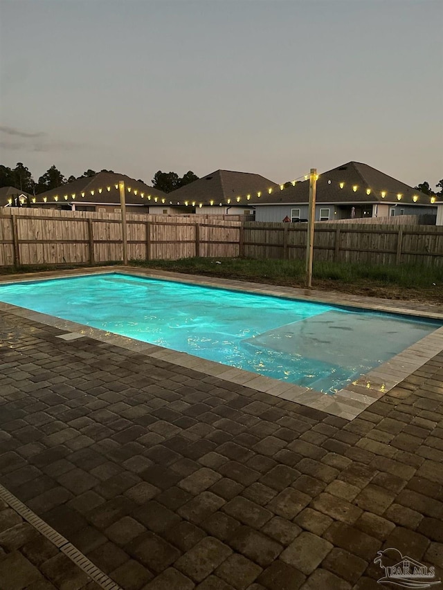 pool at dusk featuring a patio area