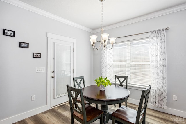 dining space with wood-type flooring, ornamental molding, and a notable chandelier