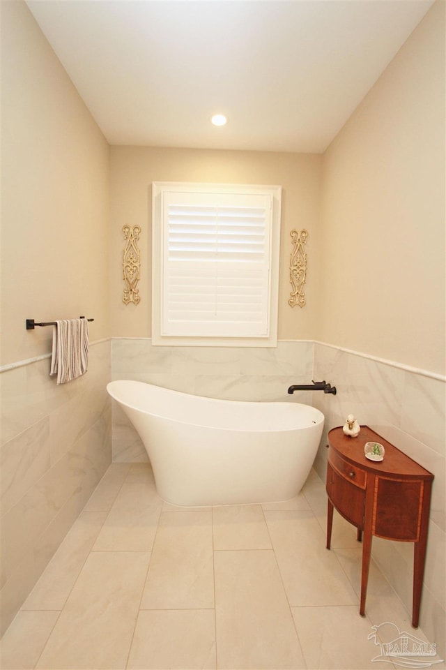 bathroom featuring a bathtub, tile patterned floors, and tile walls