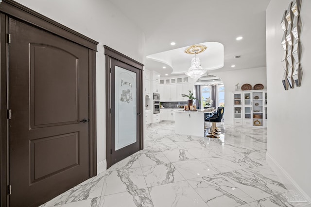 502 Deer Point Dr, Gulf Breeze, FL 32561 - hallway with baseboards, a chandelier, recessed lighting, a tray ceiling, and arched walkways