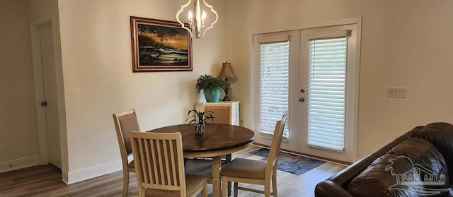 dining area with french doors, hardwood / wood-style flooring, and a notable chandelier