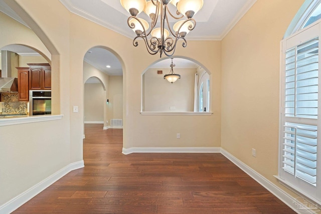 1011 Bucyrus Ln, Cantonment, FL 32533 - unfurnished dining area featuring a chandelier, dark wood finished floors, crown molding, arched walkways, and baseboards