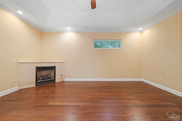 1011 Bucyrus Ln, Cantonment, FL 32533 - unfurnished living room featuring a tray ceiling, wood-type flooring, a tile fireplace, ceiling fan, and crown molding