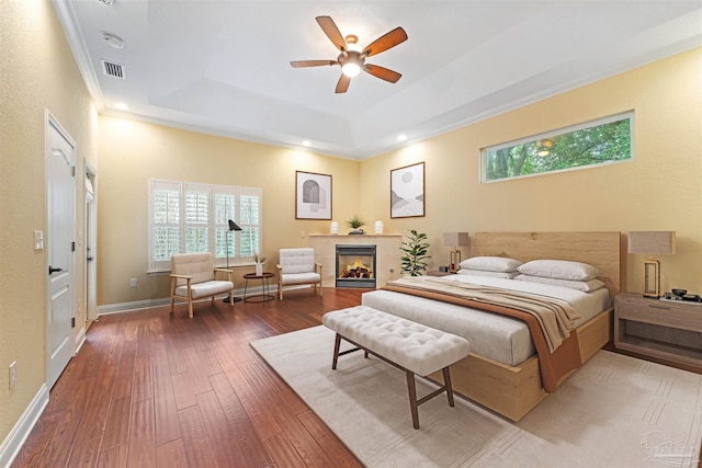 1011 Bucyrus Ln, Cantonment, FL 32533 - bedroom with hardwood / wood-style flooring, a tray ceiling, crown molding, a tiled fireplace, and a ceiling fan