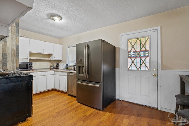 kitchen featuring white cabinetry, light hardwood / wood-style flooring, a textured ceiling, and appliances with stainless steel finishes