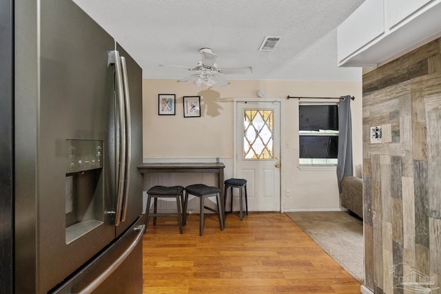 foyer entrance with ceiling fan, light wood-type flooring, and a textured ceiling