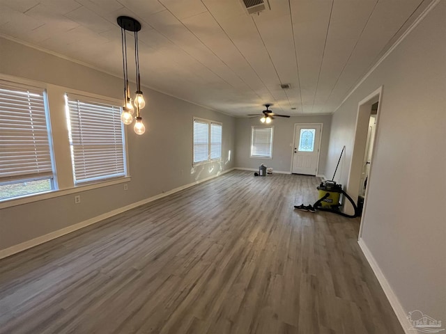 interior space with crown molding, wood finished floors, baseboards, and visible vents