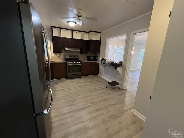 kitchen with light countertops, appliances with stainless steel finishes, under cabinet range hood, crown molding, and light wood-type flooring