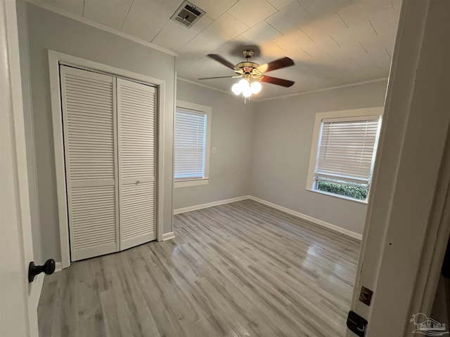 unfurnished bedroom featuring visible vents, light wood-style flooring, baseboards, and ornamental molding