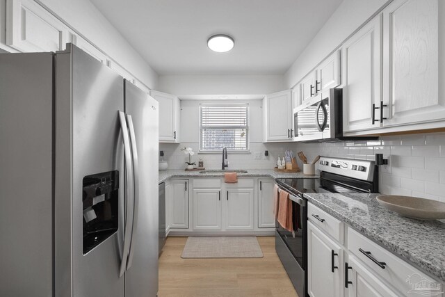 6216 Forest Pines Dr, Pensacola, FL 32526 - kitchen with appliances with stainless steel finishes, a sink, backsplash, light wood-style flooring, and white cabinetry