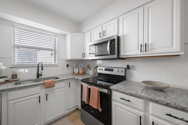 6216 Forest Pines Dr, Pensacola, FL 32526 - kitchen featuring appliances with stainless steel finishes, a sink, backsplash, white cabinetry, and light stone counters