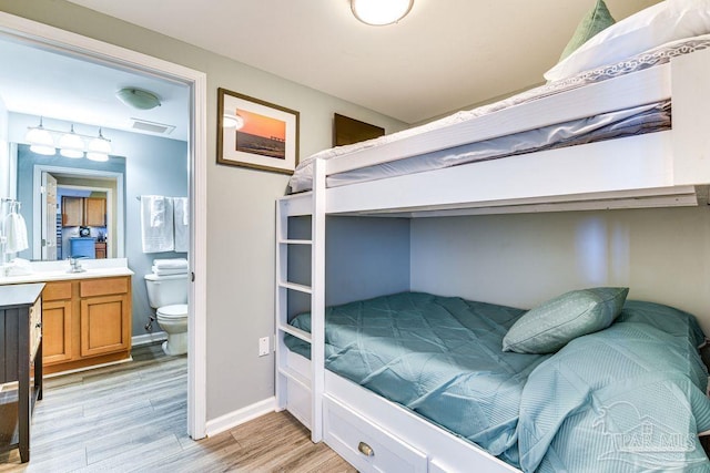 bedroom featuring sink, light wood-type flooring, and ensuite bathroom