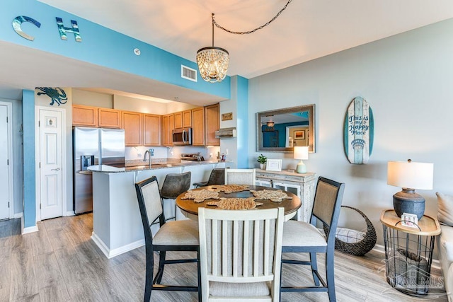 dining room with light wood-type flooring, an inviting chandelier, and sink