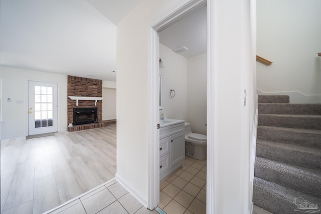 stairs with tile patterned flooring and a brick fireplace