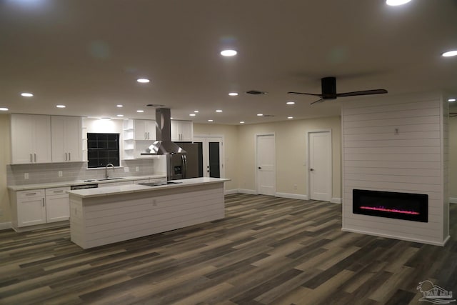 kitchen featuring visible vents, a kitchen island, light countertops, stainless steel fridge, and island range hood