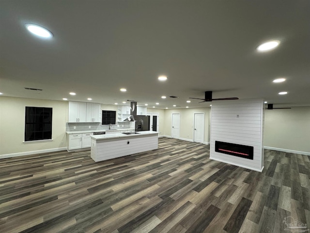 kitchen featuring open floor plan, a center island with sink, light countertops, recessed lighting, and white cabinetry