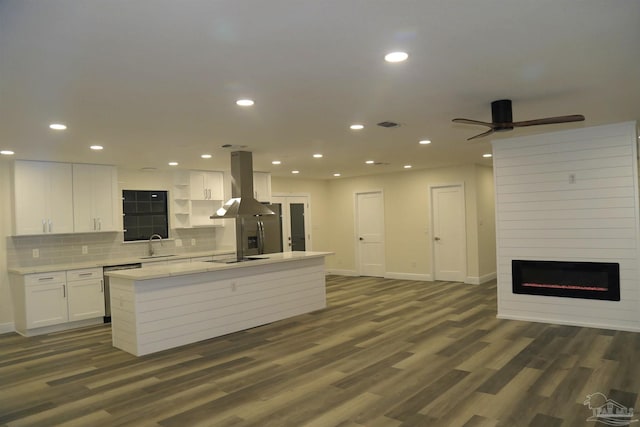 kitchen with a sink, open floor plan, island exhaust hood, white cabinets, and dark wood-style flooring