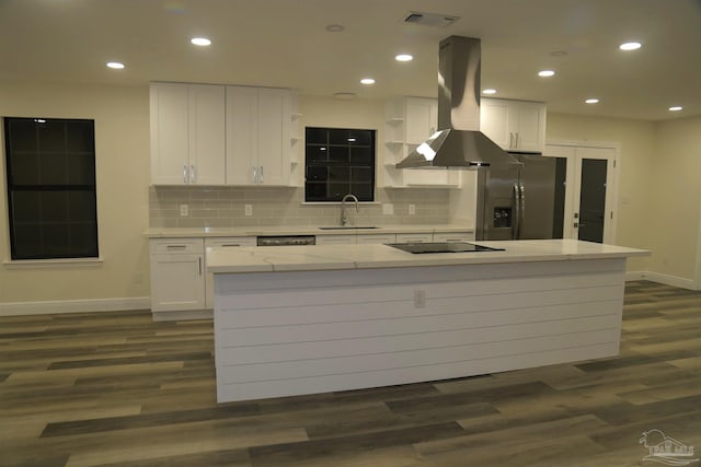 kitchen with visible vents, stainless steel refrigerator with ice dispenser, island exhaust hood, a sink, and white cabinets