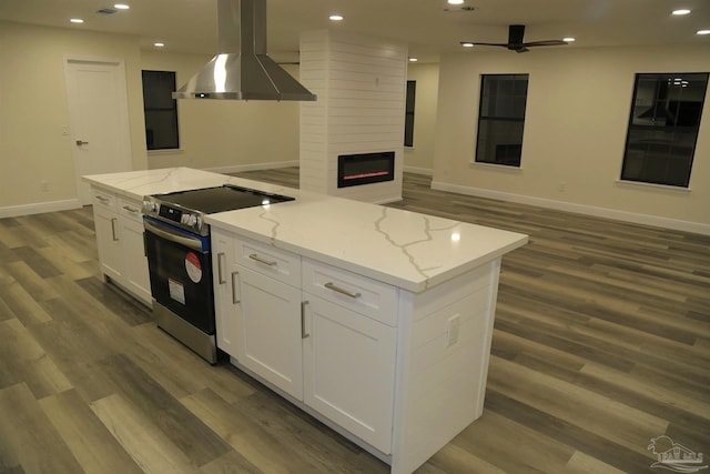 kitchen featuring electric stove, open floor plan, white cabinetry, a large fireplace, and island range hood