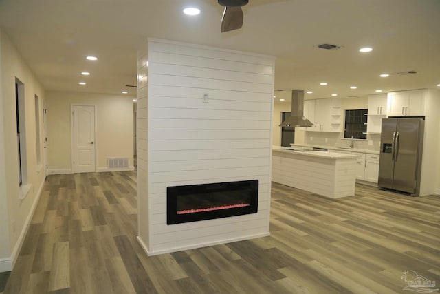 kitchen with light countertops, recessed lighting, stainless steel refrigerator with ice dispenser, island range hood, and a sink