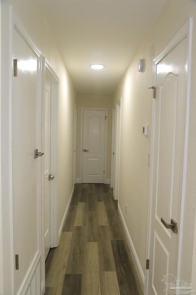 hallway with baseboards and dark wood-style floors