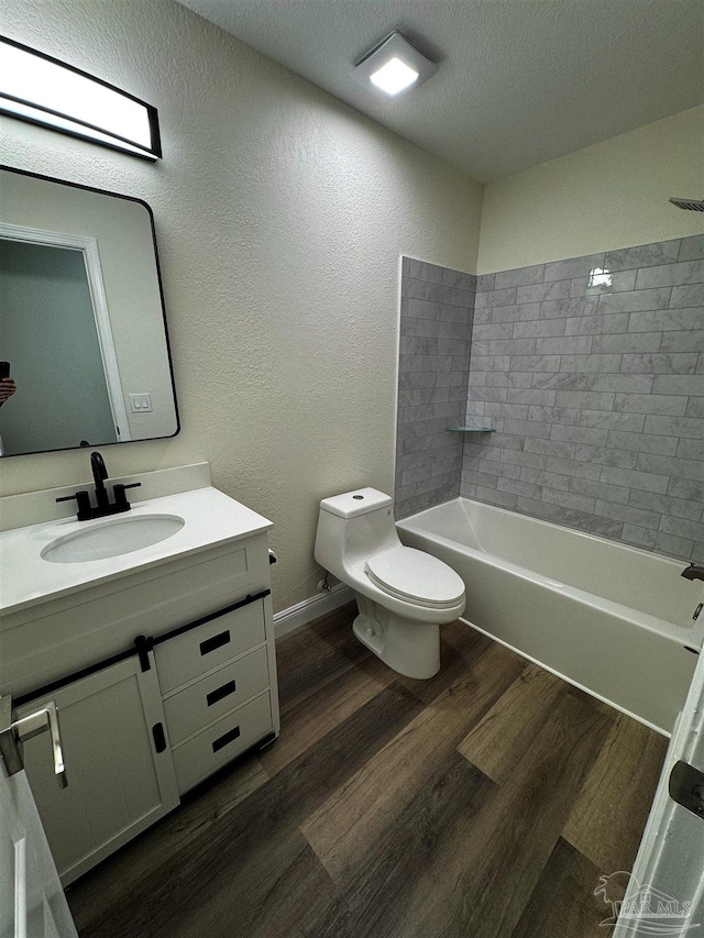 full bath featuring toilet, vanity, bathtub / shower combination, wood finished floors, and a textured ceiling