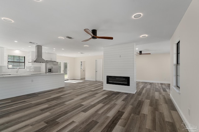 unfurnished living room with visible vents, a large fireplace, dark wood-type flooring, recessed lighting, and a sink