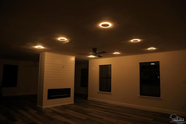 empty room with a ceiling fan, dark wood-style floors, baseboards, recessed lighting, and a large fireplace