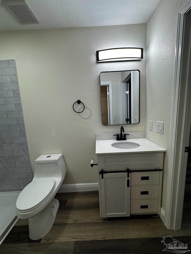 bathroom with visible vents, baseboards, toilet, wood finished floors, and vanity