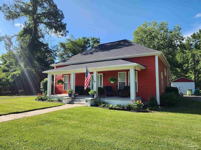 210 Mcrae St, Atmore, AL 36502 - bungalow featuring a porch, a front yard, an outbuilding, and a shingled roof